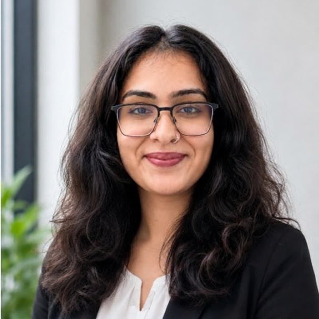 Suhani Bhatia, wearing a black blazer and glasses